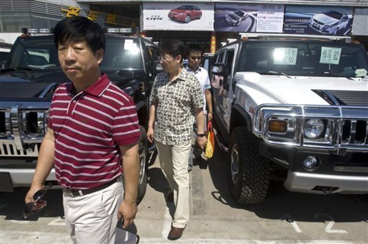 Customers walk between two Hummer vehicles in a parking lot of an auto market in Beijing Wednesday, June 3, 2009. China's Sichuan Tengzhong Heavy Industrial Machinery Co., said Tuesday it is buying the maker of luxury military-style SUVs from General Motors Corp. (AP Photo/Alexander F. Yuan)