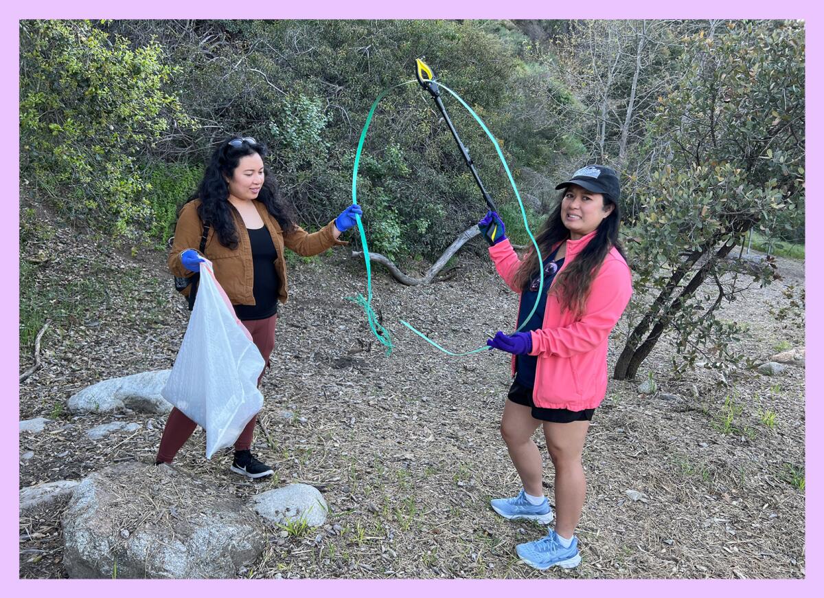 Two women hold a 7-foot-long piece of plastic they picked up on a trail.