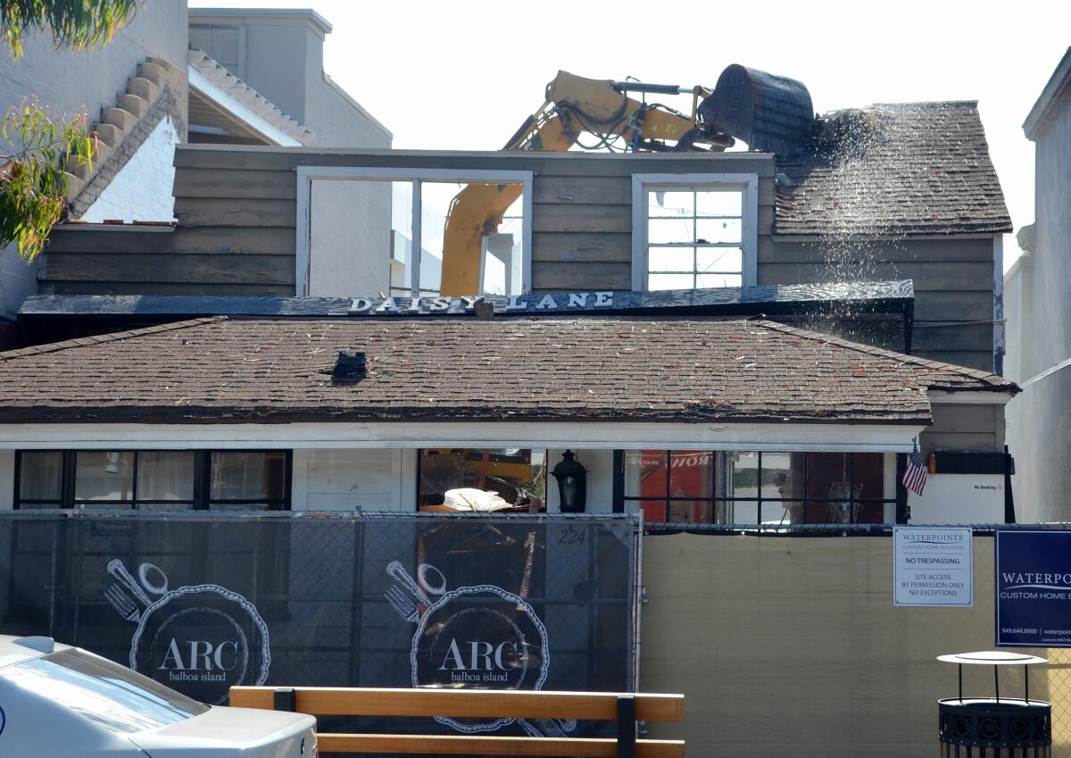 A "mini excavator" takes a bite from the roof of Daisy Lane on Balboa Island.