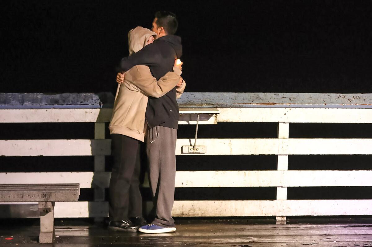 A couple embrace at a candlelight vigil for Tatum Goodwin at the San Clemente pier.