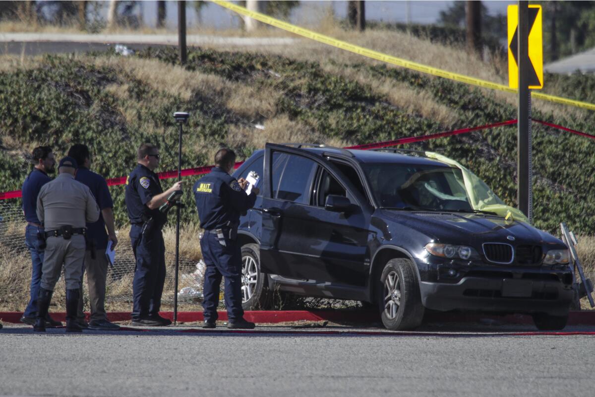 Police officers stand next to a crashed SUV with its passenger side door open