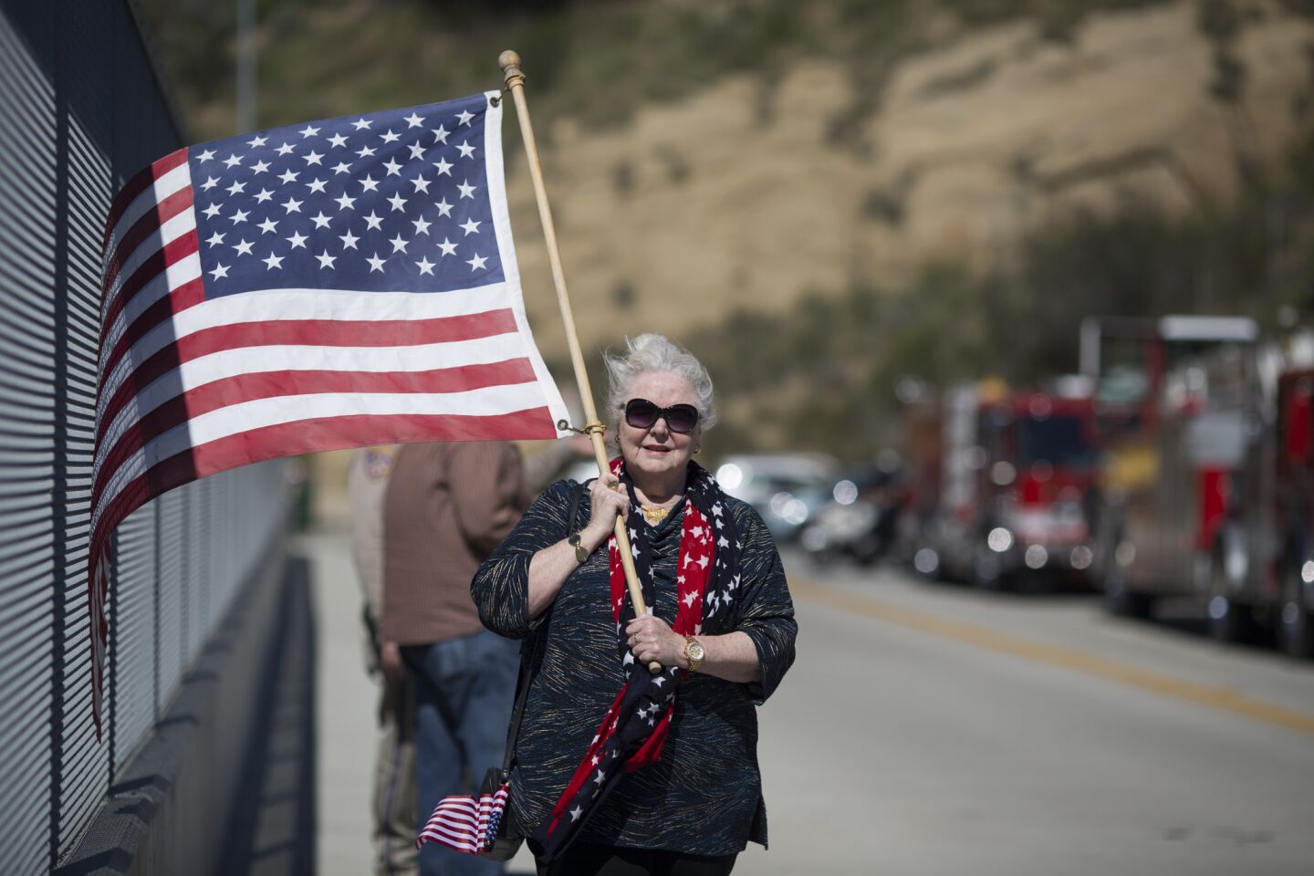 Rachel Handy carries an American flag after watching the motorcade escorting the body of former first lady Nancy Reagan pass by on the Ronald Reagan Freeway en route to the Ronald Reagan Presidential Library.