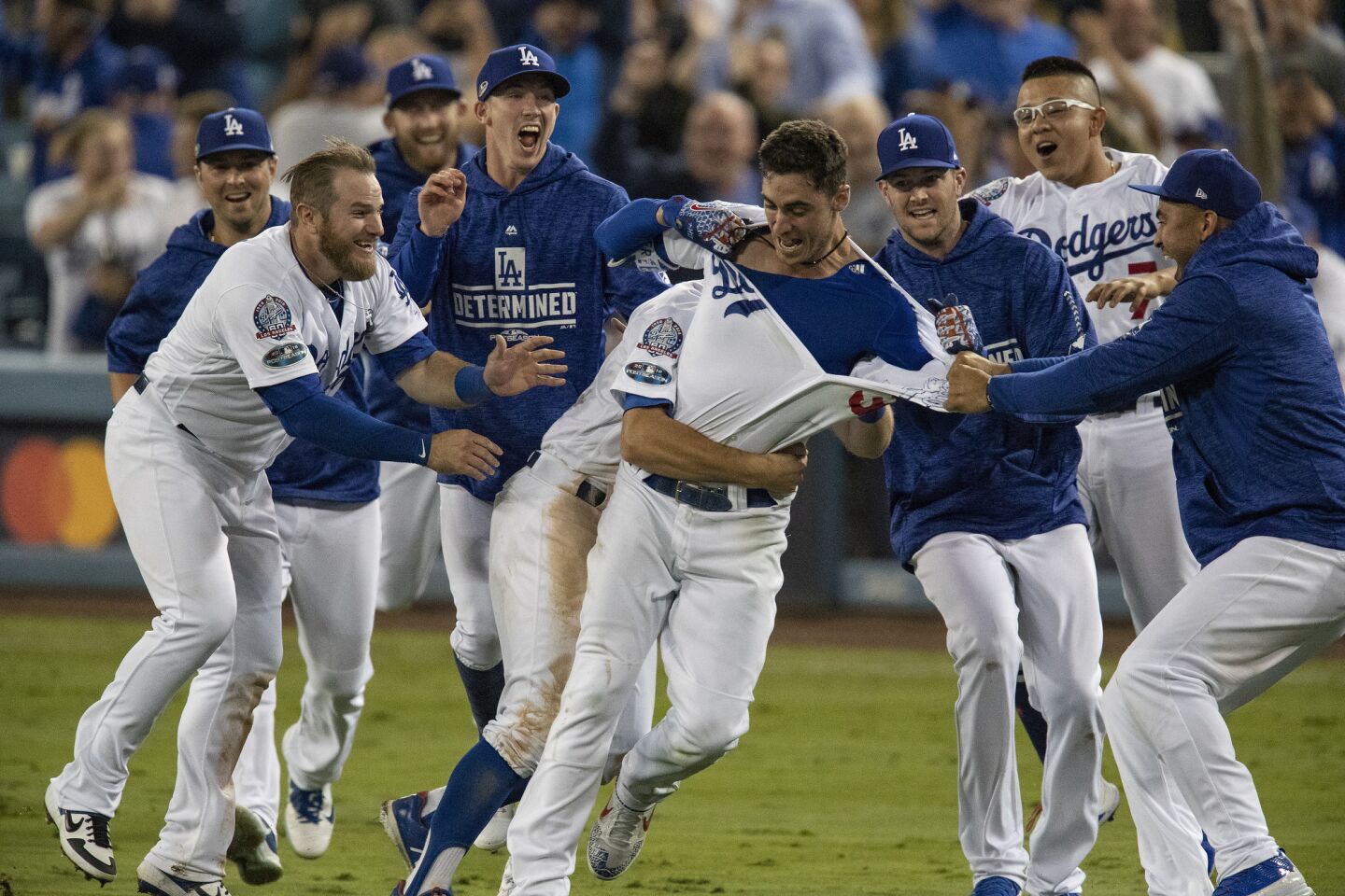 Teammates mob Dodgers center fielder Cody Bellinger after he hit the game winning RBI in the 13th inning during Game 4 of the NLCS at Dodger Stadium on October 16, 2018.
