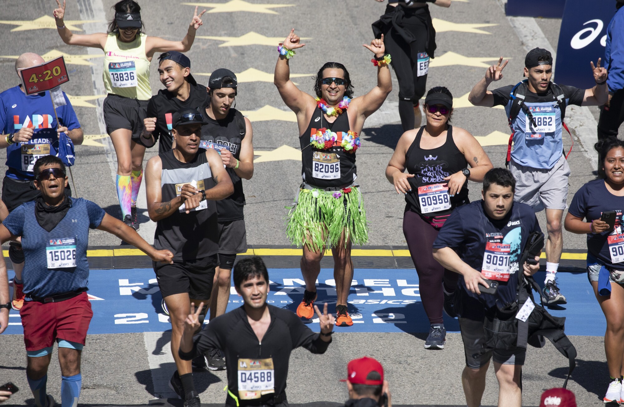 Runners cross the finish line on Avenue of the Stars in Century City during the LA Marathon on Sunday