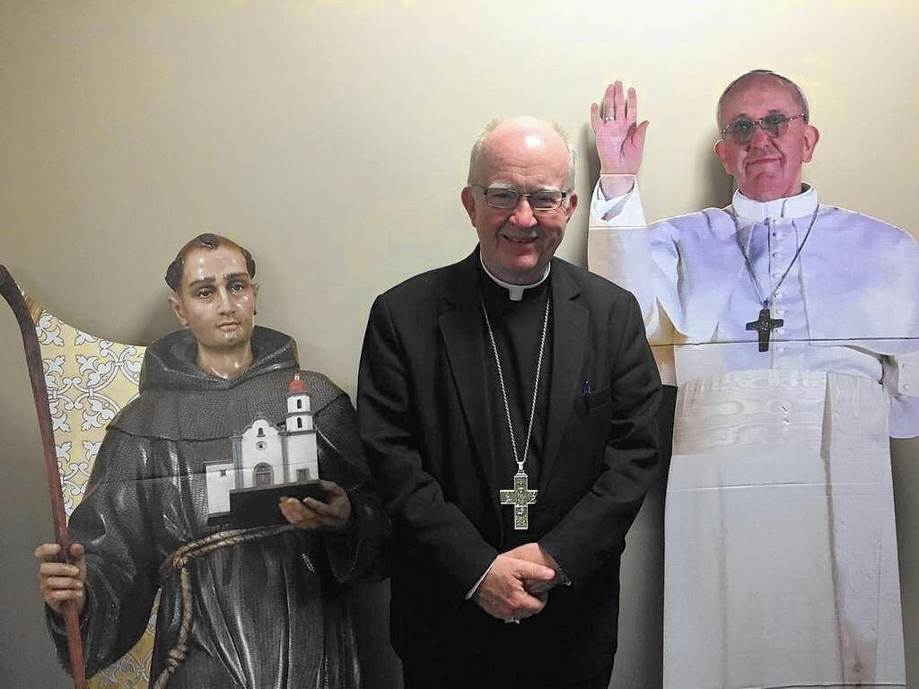 Bishop Vann stands before cardboard cutouts of St. Junipero Serra and Pope Francis before a St. Junipero Serra celebration Mass at J Serra High School.