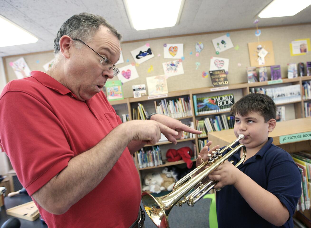 LAUSD traveling instrumental music teacher David Early gestures as Sarkis Altunyan, 7, hits the right note on a trumpet during a program at the Grandview Library on Thursday, May 8, 2014, that gives children familiarity with musical instruments.