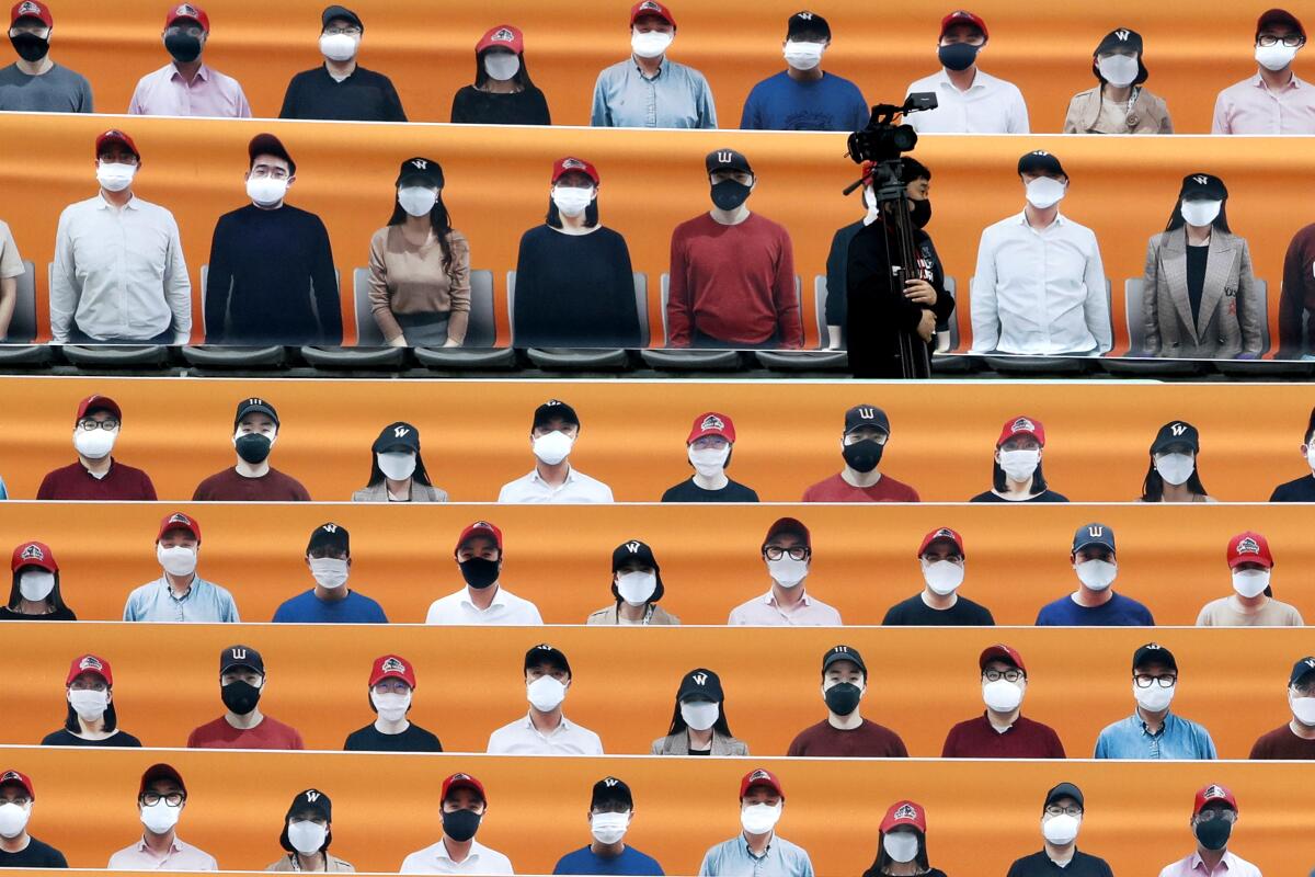 A TV cameraman walks through the spectators' seating area, which is covered with pictures of fans, before the start of a baseball game between the Hanwha Eagles and SK Wyverns in South Korea.