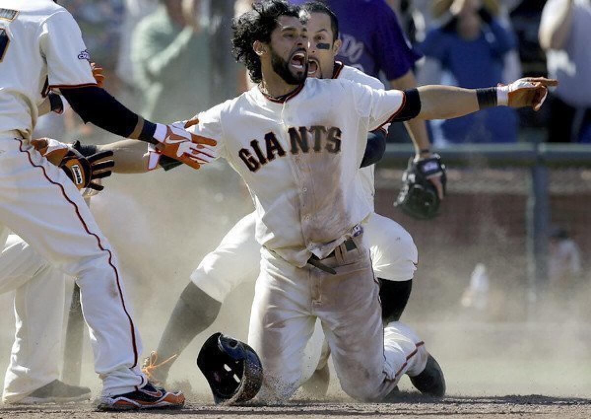 San Francisco's Angel Pagan gives the safe sign after hitting a game-winning inside-the-park home run against the Colorado Rockies on Saturday at AT&T; Park.