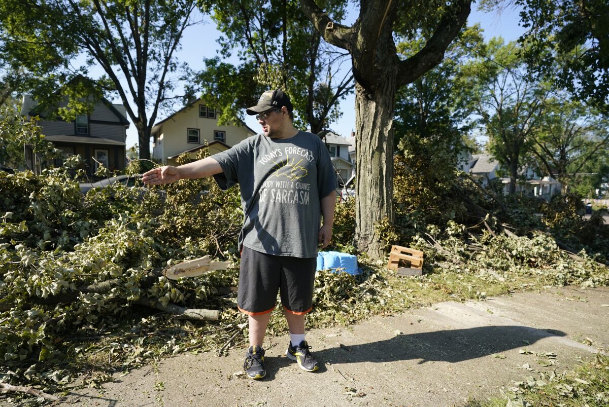 Eric Fish takes a break from hauling downed branches in front of his home, Friday, Aug. 14, 2020, in Cedar Rapids, Iowa. The storm that struck Monday morning left tens of thousands of Iowans without power as of Friday morning. (AP Photo/Charlie Neibergall)