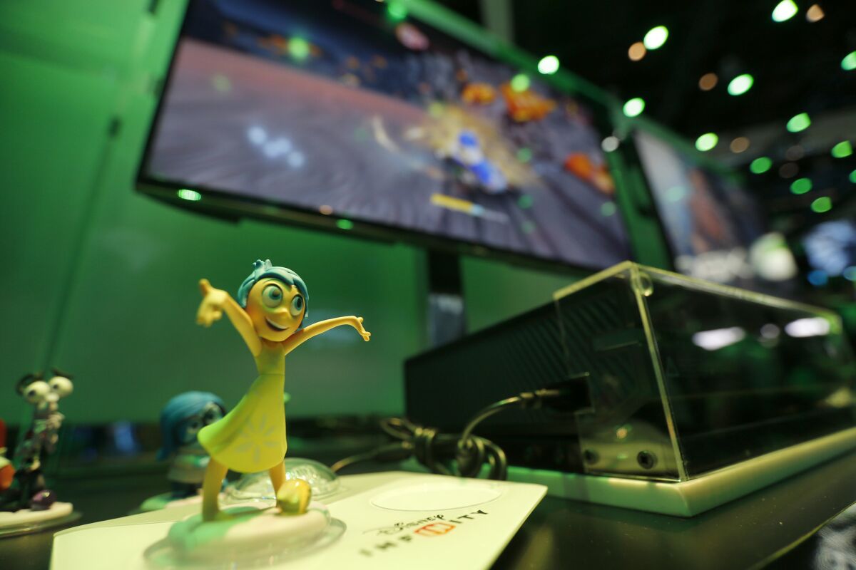 At the E3 video game convention in Los Angeles last year, the character Joy from the Disney movie "Inside Out" is used as the main character while a gamer plays Disney Infinity on the Xbox system. The game's sluggish sales lead Disney to restructure. (Allen J. Schaben / Los Angeles Times)
