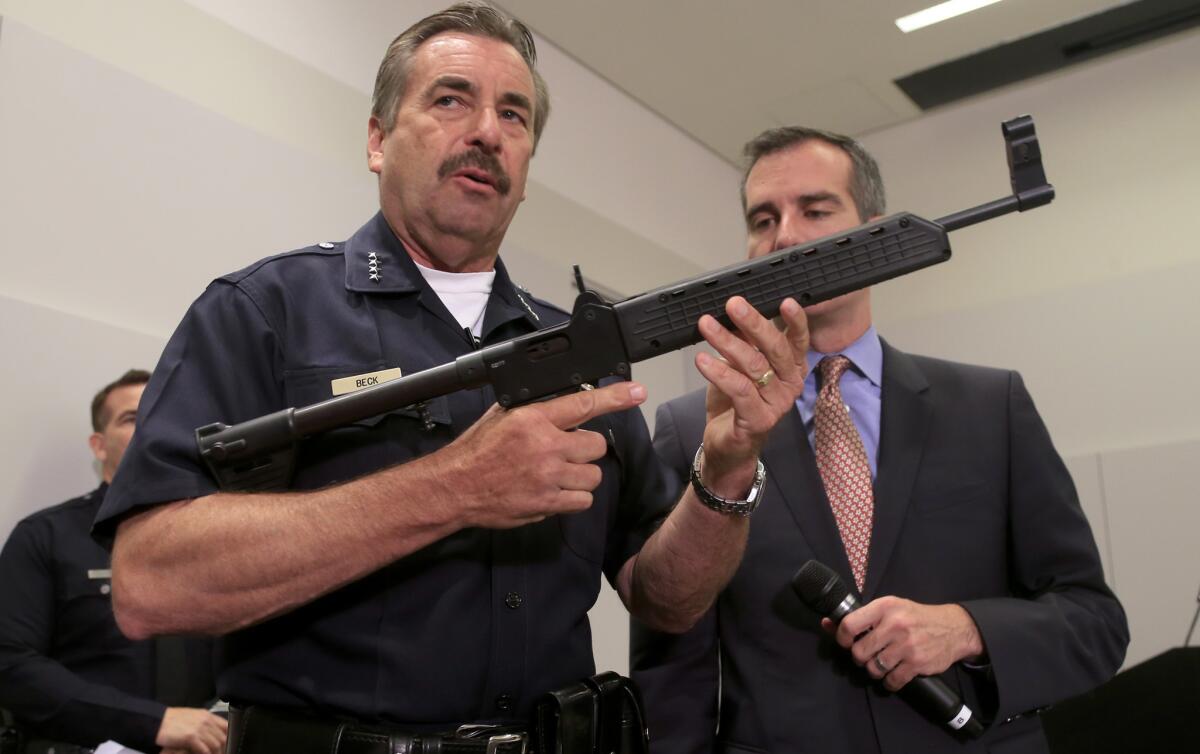 Los Angeles Police Chief Charlie Beck holds a collapsible assault weapon surrendered during a citywide gun buyback program. Behind him is Mayor Eric Garcetti.