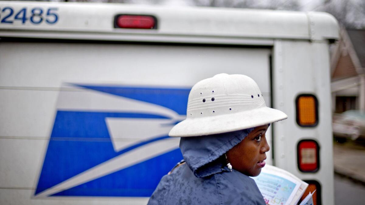 In this 2014 photo, U.S. Postal Service letter carrier Jamesa Euler delivers mail in the rain in Atlanta.