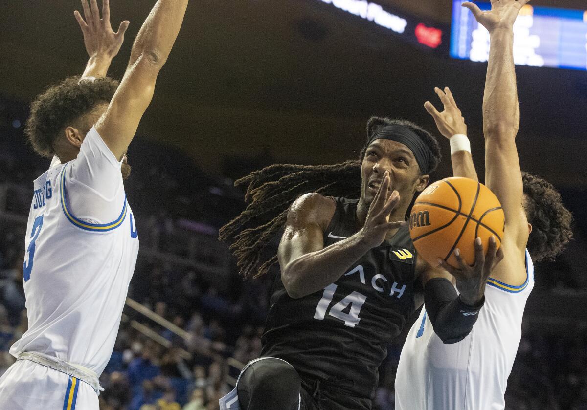 Long Beach State's Colin Slater splits Bruins Johnny Juzang and Jules Bernard on his way to the basket.