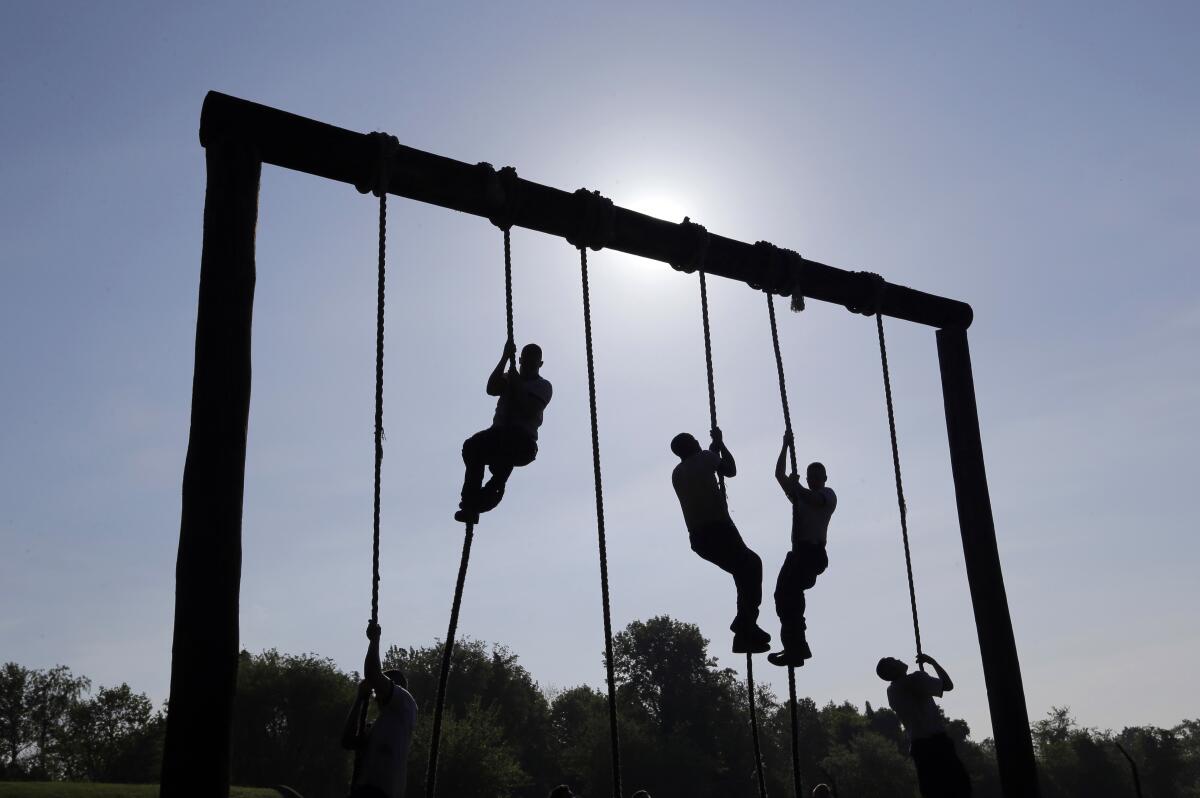 FILE - Freshman midshipmen, known as plebes, climb ropes on an obstacle course during Sea Trials.