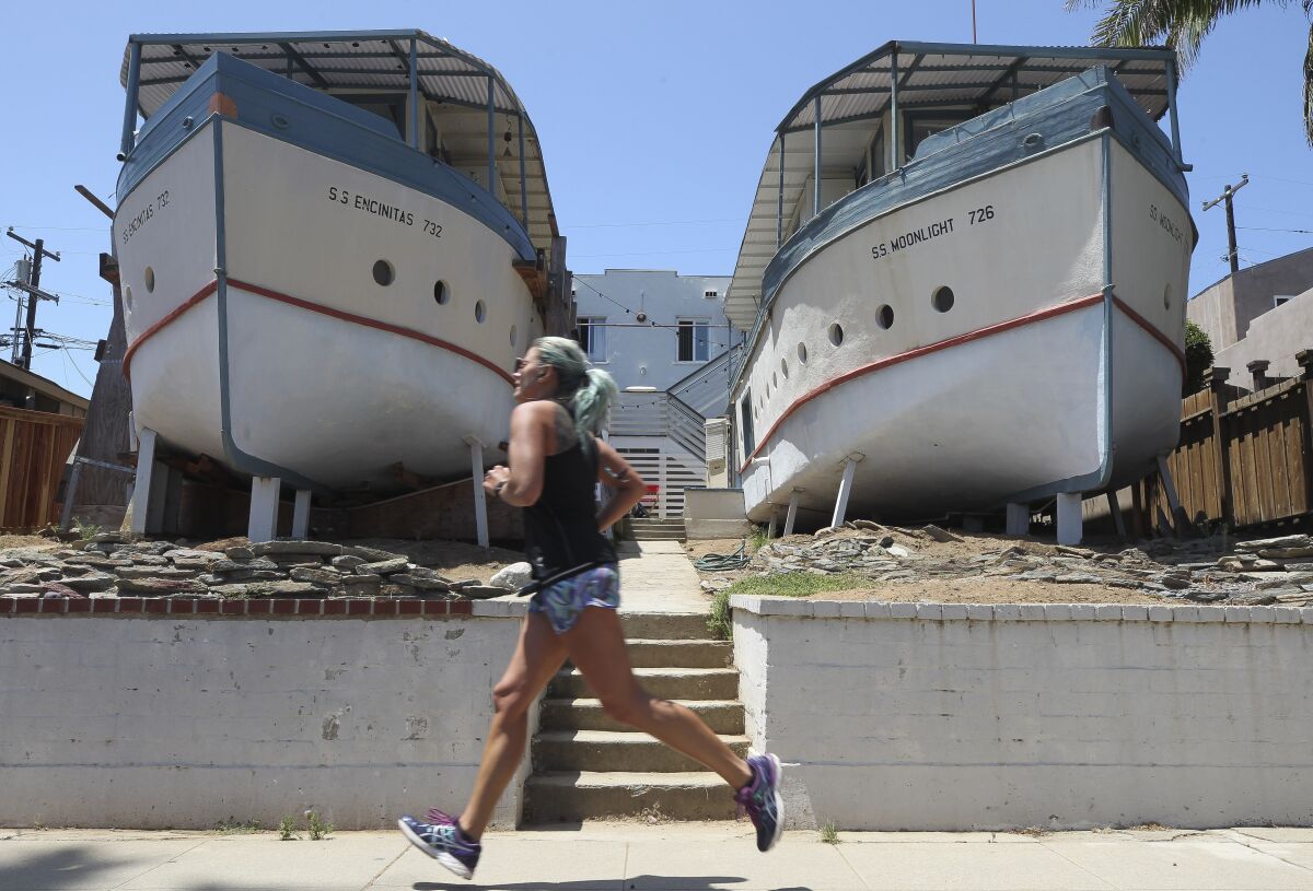 A woman jogs past the Encinitas Boathouses, located on Third Street, on Wednesday, July 31, 2019 in Encinitas.