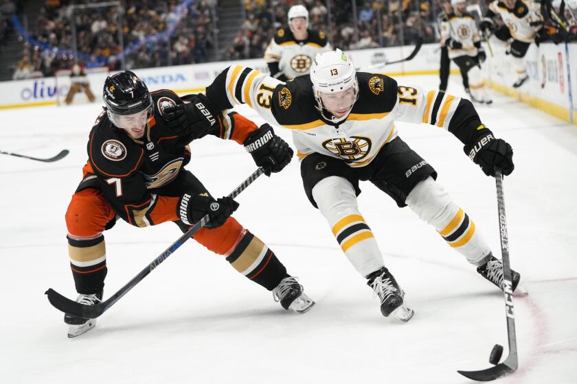 Boston Bruins' Charlie Coyle (13) moves the puck under pressure by Anaheim Ducks' Jayson Megna.