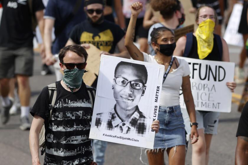 FILE - A demonstrator carries an image of Elijah McClain during a rally and march in Aurora, Colo., June 27, 2020. A Colorado judge on Friday, Sept. 16, 2022 responded to a request by a coalition of news organizations to release an amended autopsy report for Elijah McClain, a 23-year-old Black man who died after a 2019 encounter with police, by ruling the report be made public only after new information it contains is redacted. (AP Photo/David Zalubowski, File)