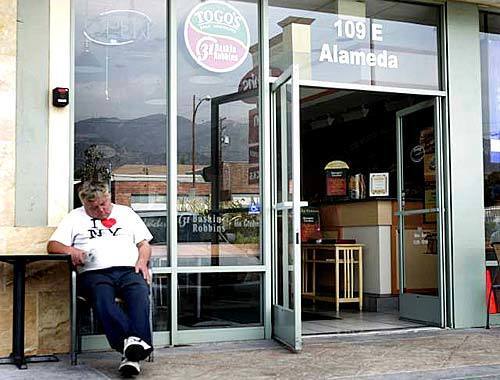 A customer takes a nap outside the darkened Togo/Baskin Robbin 31 Flavors store in Burbank during the blackout.