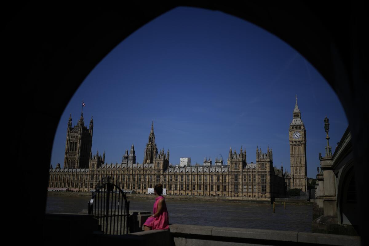 A woman poses for her own phone picture framed by an underpass arch on the south bank of the River Thames backdropped by the Elizabeth Tower, known as Big Ben, and the Houses of Parliament, in London, Monday, July 11, 2022. Candidates to replace Boris Johnson as Britain's prime minister are scattering tax-cutting promises to their Conservative Party electorate, as party officials prepare Monday to quickly narrow the crowded field of more than ten candidates. (AP Photo/Matt Dunham)