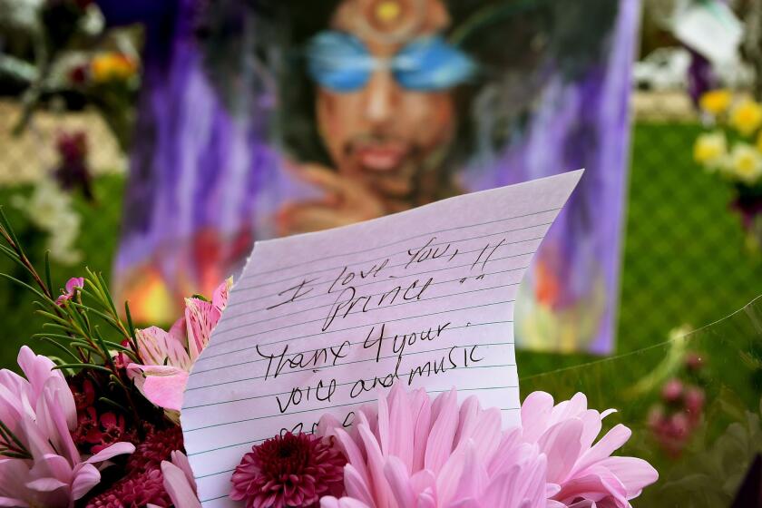 A Prince fan holds flowers outside the Paisley Park compound in Minneapolis on April 22, 2016. Prince died April 21, 2016.