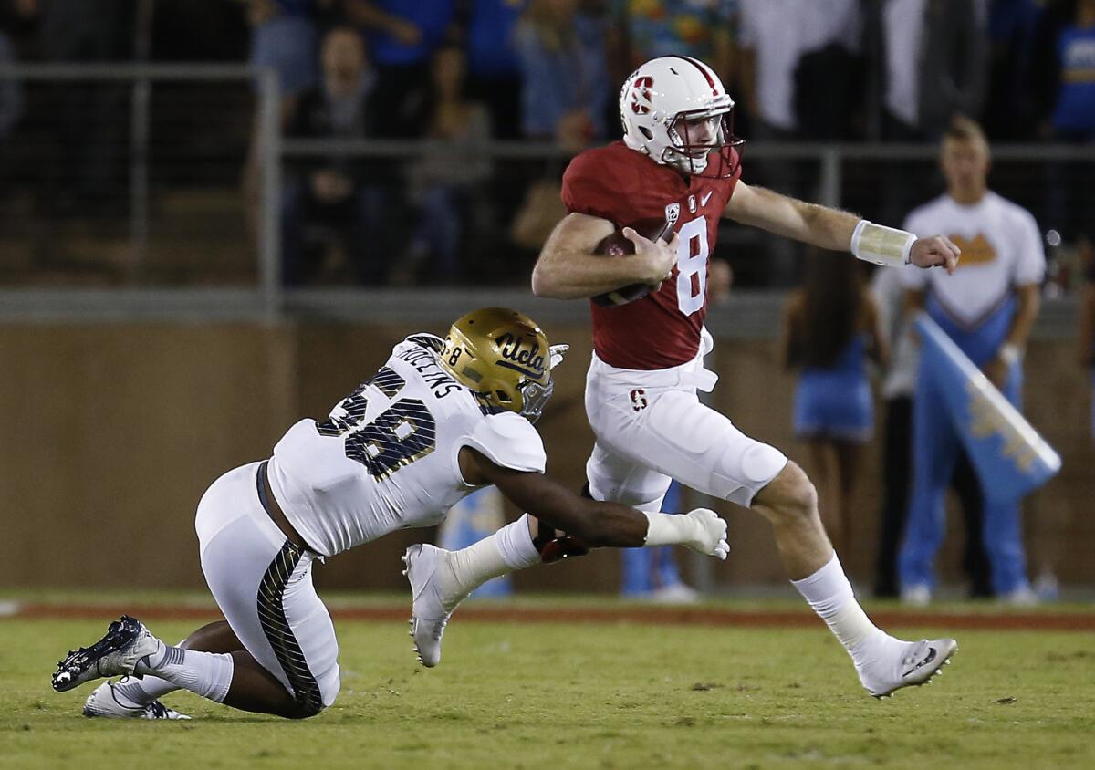 Stanford quarterback Kevin Hogan scrambles away from UCLA linebacker Deon Hollins during the first half on Thursday.