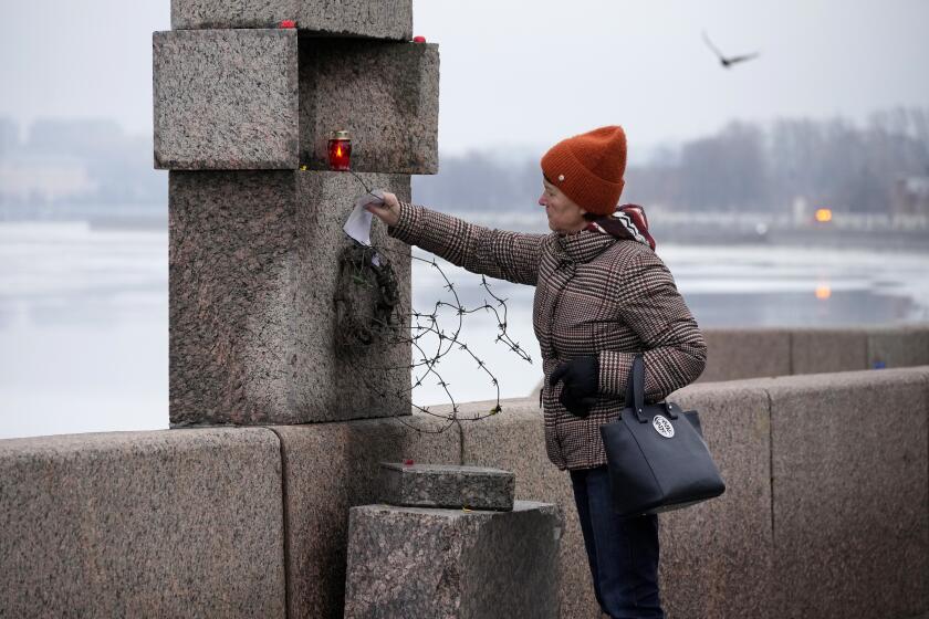 A woman places a piece of paper with words of grief for Alexei Navalny paying the last respect to him at the Memorial to Victims of Political Repression in St. Petersburg, Russia, Saturday, Feb. 24, 2024. Navalny, 47, Russia's most well-known opposition politician, unexpectedly died on Feb. 16 in the penal colony, prompting hundreds of Russians across the country to stream to impromptu memorials with flowers and candles. (AP Photo/Dmitri Lovetsky)