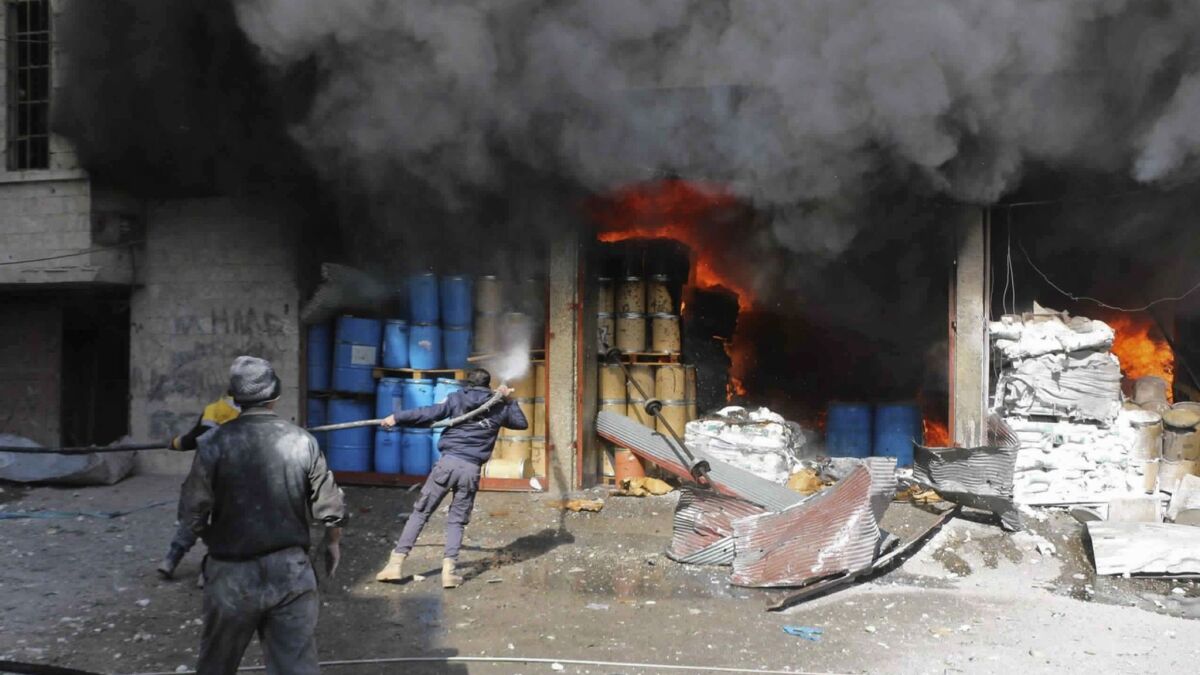 Members of a Syrian civil defense group extinguish a fire at a store during airstrikes and shelling by Syrian government forces in Ghouta, Syria, on Feb. 20.