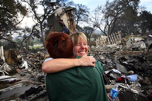 Melissa Puyot celebrates with her friend Kris Hoyt (in green) on Sunday after finding cherished mementos in her destroyed home in Ramona. The small community lost 52 homes in the Witch fire that burned almost 200,000 acres. "This is a positive," Puyot said. "I will not let this fire beat me down."