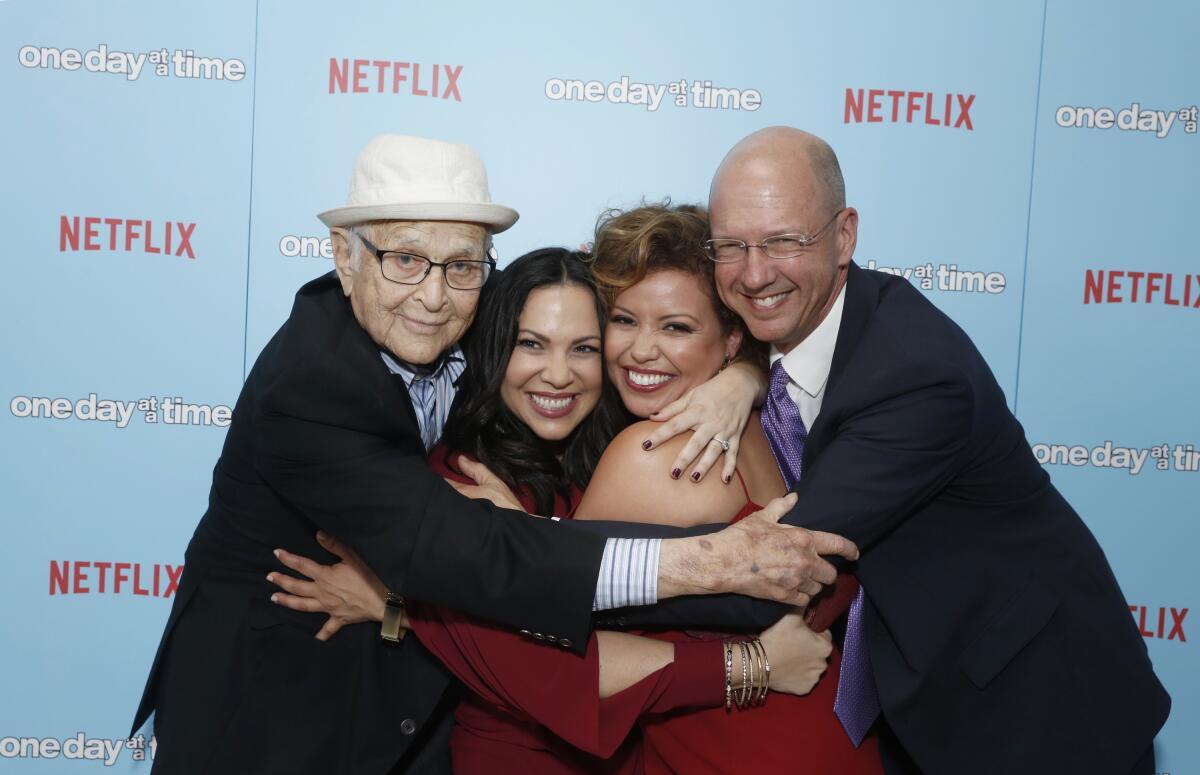Norman Lear, Gloria Calderon Kellett, Justina Machado and Mike Royce embrace at a Netflix event.