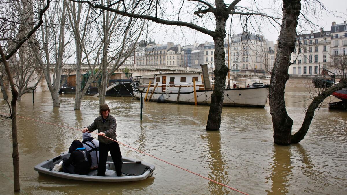 People use a dinghy to reach a barge on the River Seine in Paris on Jan. 27, 2018.