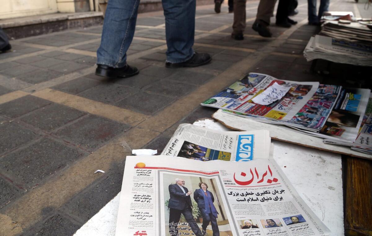 A copy of the newspaper Iran, with a photo of Iranian Foreign Minister Mohammad Javad Zarif and European Union diplomat Catherine Ashton and a headline reading "The bells for the Geneva nuclear agreement will toll today," is displayed on the ground in Tehran.