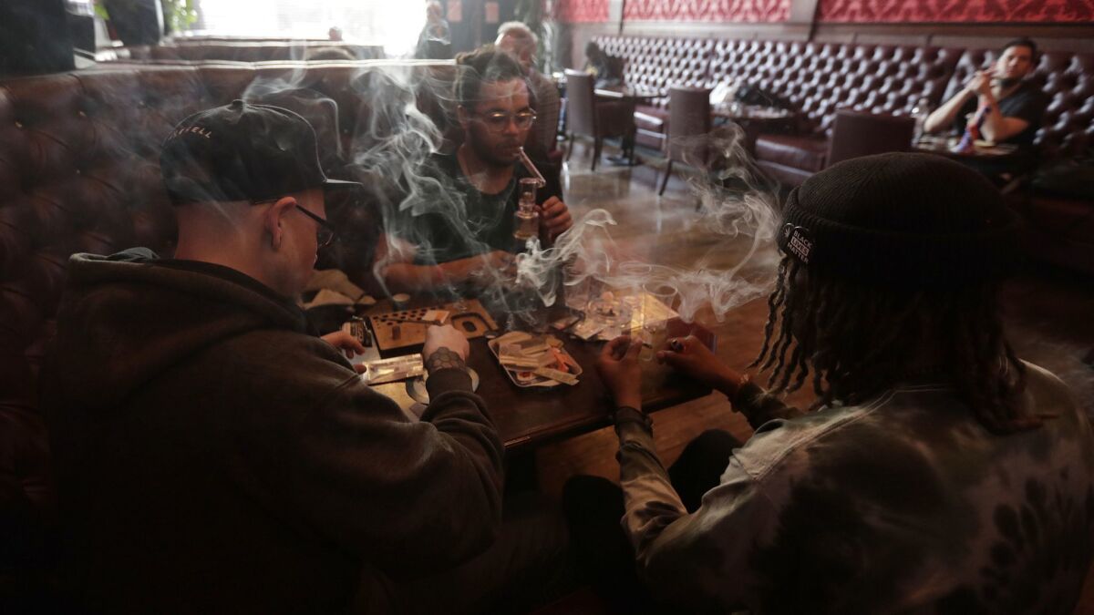 Customers smoke marijuana while sitting in a booth in the smoking lounge at Barbary Coast Dispensary in San Francisco. The city plans to issue more permits for marijuana smoking lounges this year after health officials finalize updated regulations.