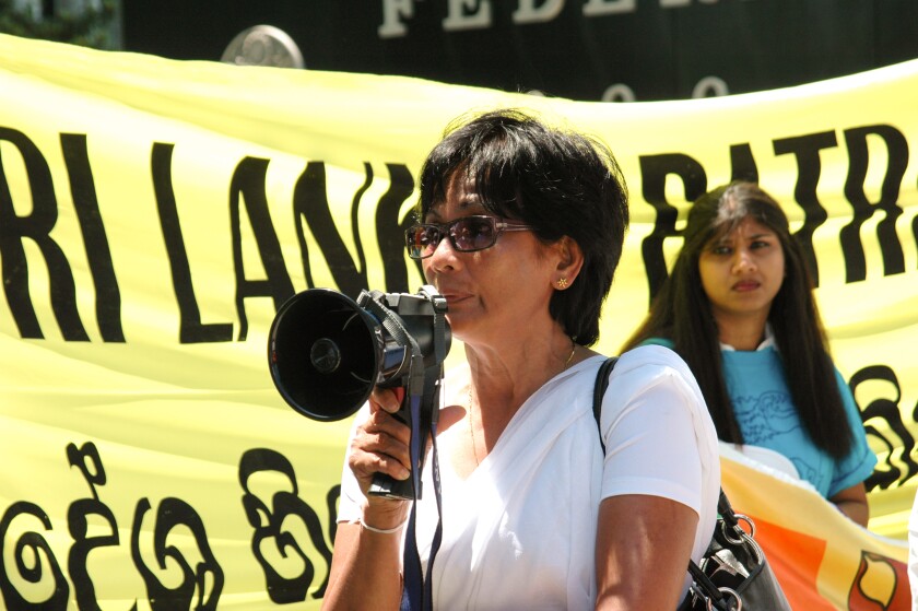 Sri Lankan journalist Hassina Leelarathna holds a megaphone in front of federal building.