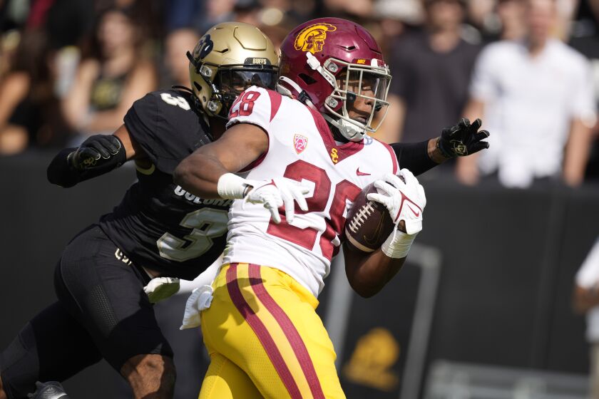 Southern California running back Keaontay Ingram, right, is dragged down by Colorado cornerback Christian Gonzalez.