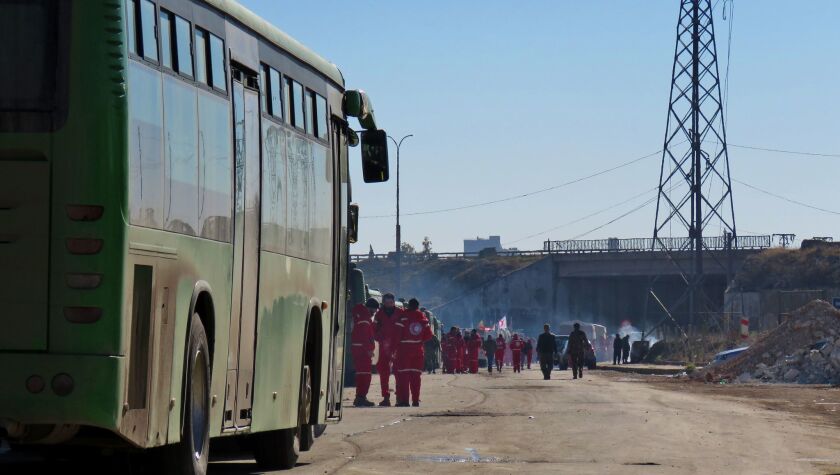 Staff of the Syrian Red Crescent stand next to buses which were to be used to evacuate rebel fighters and their families from rebel-held areas of Aleppo on Dec. 15.