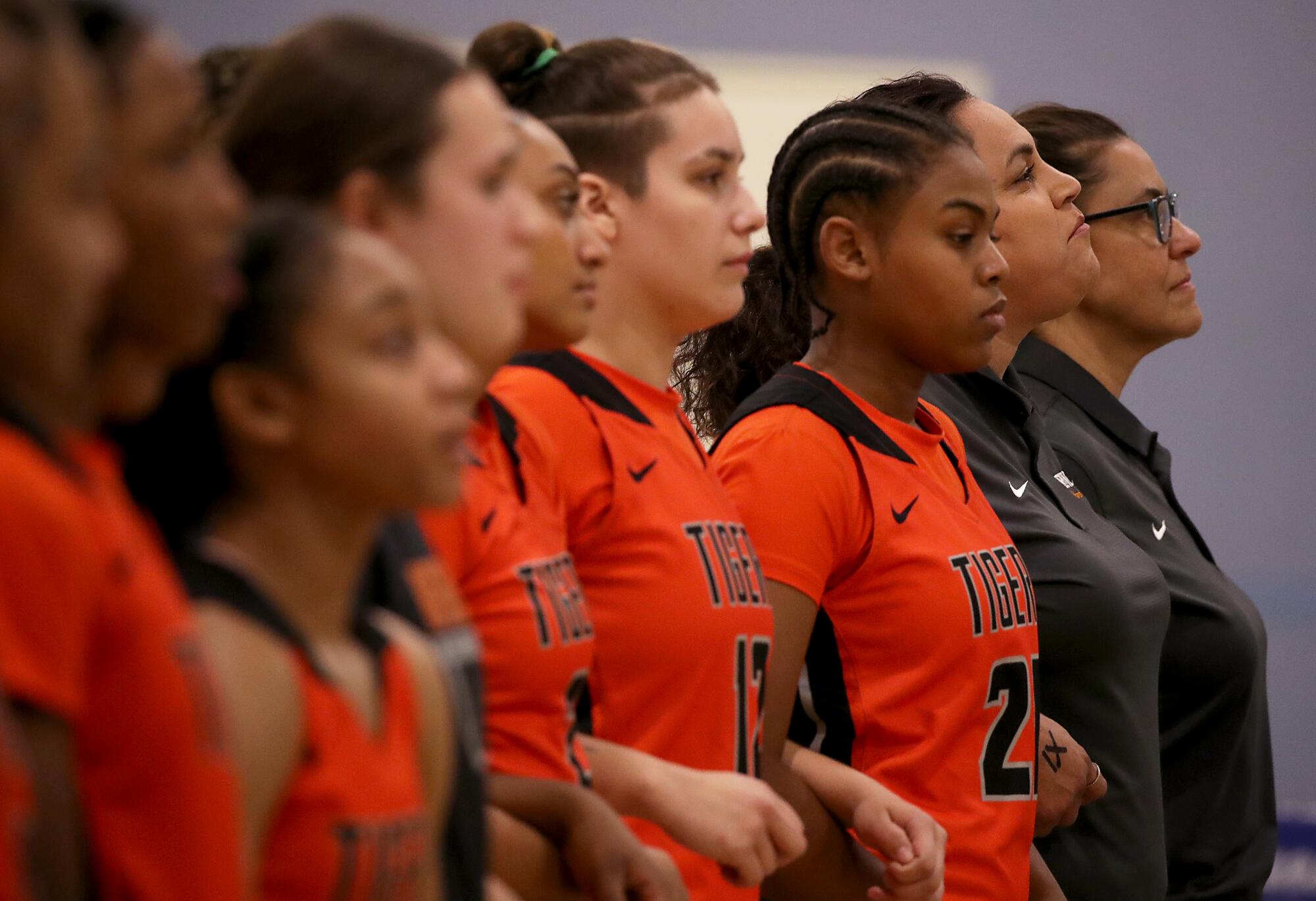 Players on the Riverside City College women's basketball and coach Alicia Berber stand during the national anthem.