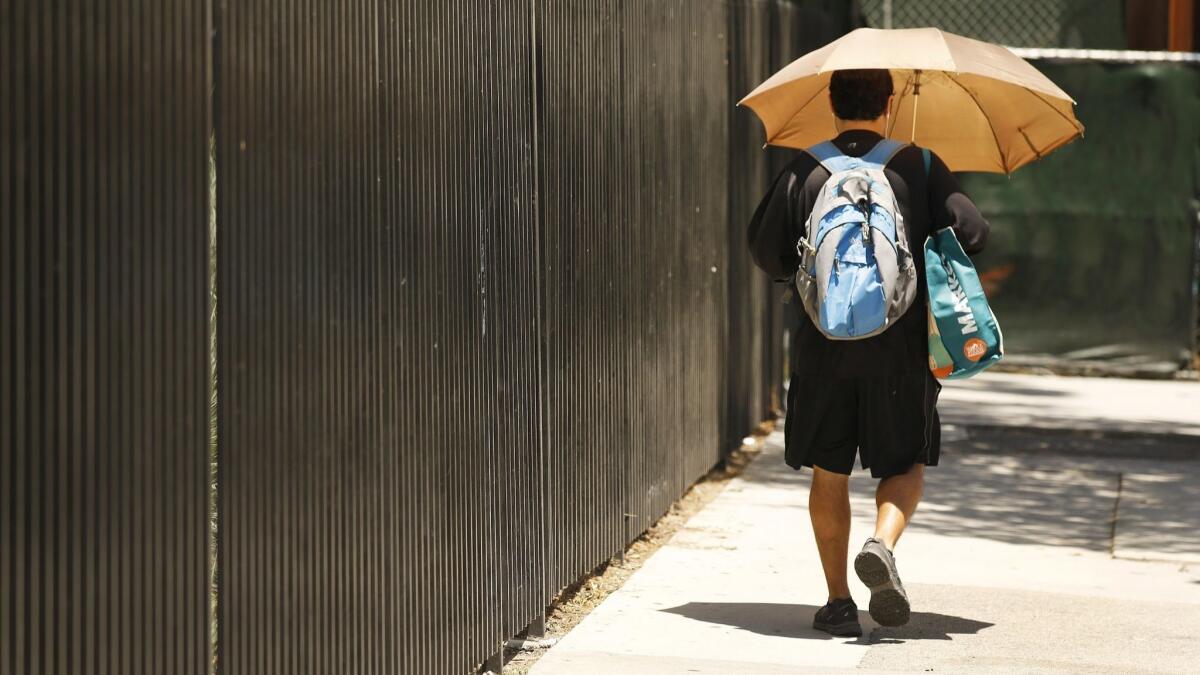 An umbrella, handy for showers less than a month ago, shades a Southland pedestrian from the sun June 10.