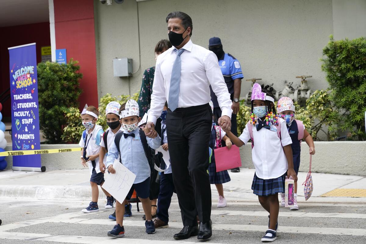 Miami-Dade schools Supt. Alberto Carvalho walks with school children wearing masks