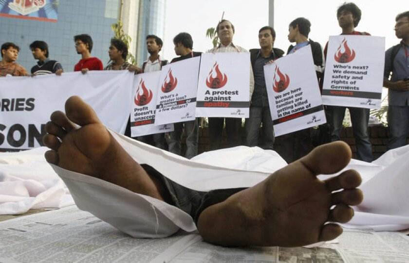 Bangladeshis protest, with some lying on the ground posing as dead bodies, as they condemn the death of workers in a garment factory fire.