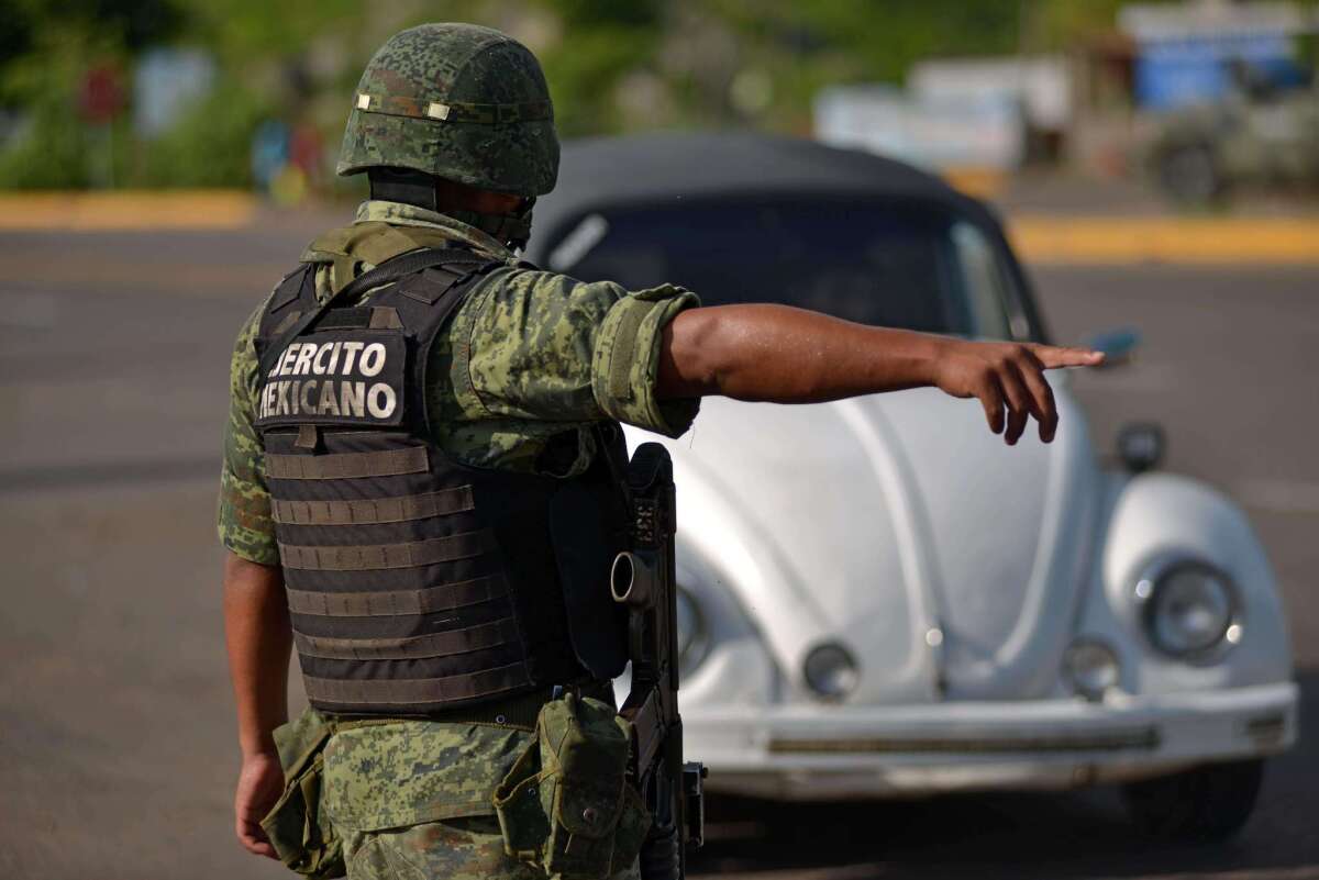 A Mexican soldier stops a vehicle at a checkpoint Wednesday on the highway connecting Badiraguato, Joaquin "El Chapo" Guzman's hometown, and Santiago de Los Caballeros, in Sinaloa state, Mexico.