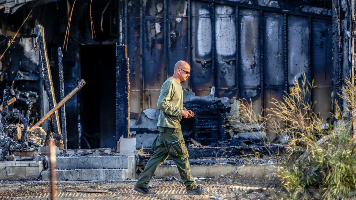 Riverside Sheriff investigator in front of the charred remains of board-and-care facility in Temecula, where firefighters found the remains of five people inside in late August.