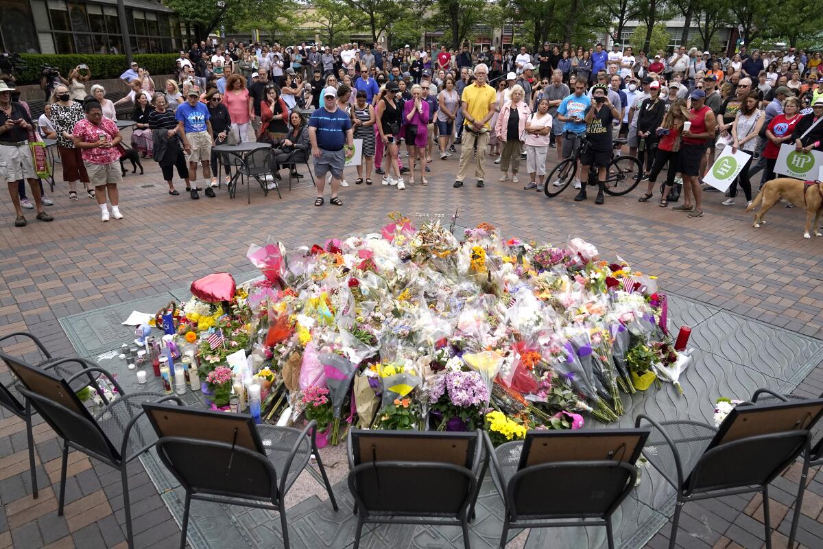 Local residents stand for a two-minute moment of silence at 10:14 a.m. at a memorial Monday, July 11, 2022, in Highland Park, Ill., to the seven people who lost their lives during the town's Fourth if July parade. (AP Photo/Charles Rex Arbogast)