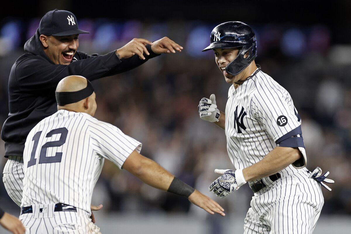 New York Yankees' Giancarlo Stanton, right, is congratulated by Nestor Cortes Jr. and Rougned Odor (12) after hitting a walkoff single during the 11th inning of a baseball game against the Baltimore Orioles, Friday, Sept. 3, 2021, in New York. (AP Photo/Adam Hunger)
