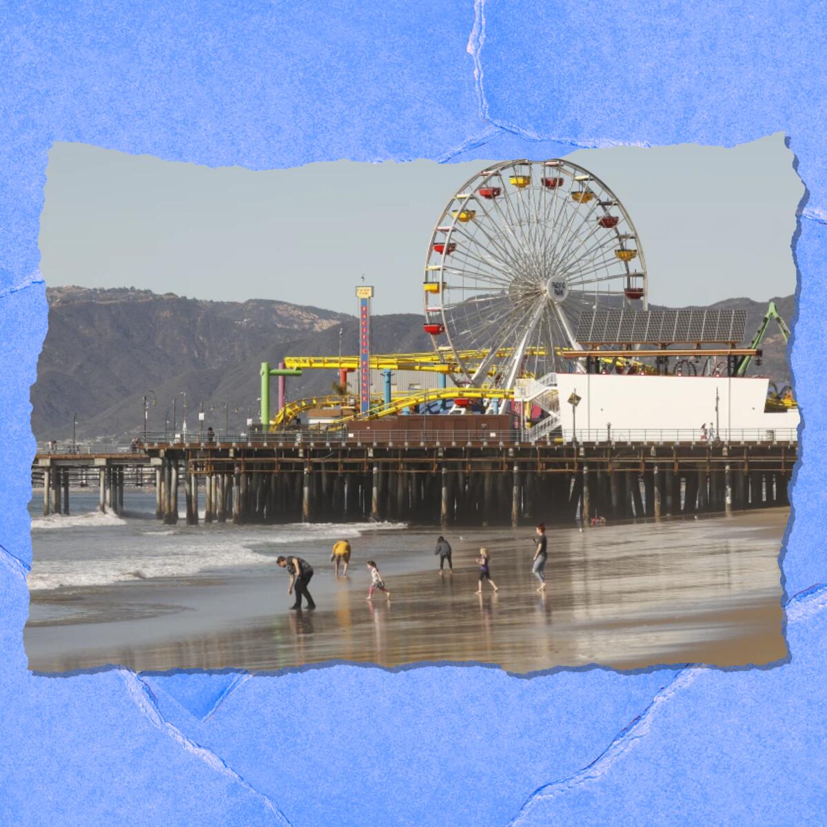 A pier with a Ferris wheel is seen from a distance. People in the foreground walk on the beach.