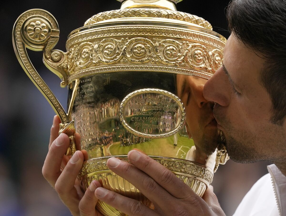 Serbia's Novak Djokovic kisses the winners trophy as he poses for photographers after he defeated Italy's Matteo Berrettini in the men's singles final on day thirteen of the Wimbledon Tennis Championships in London, Sunday, July 11, 2021. (AP Photo/Kirsty Wigglesworth)