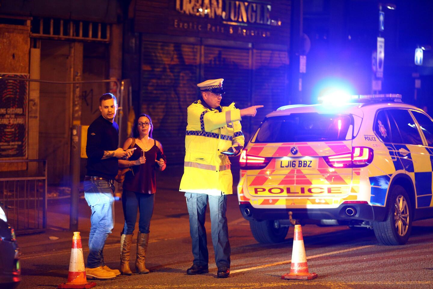 Police stand by a cordoned-off street close to the Manchester Arena on Monday night following an explosion after an Ariana Grande concert.