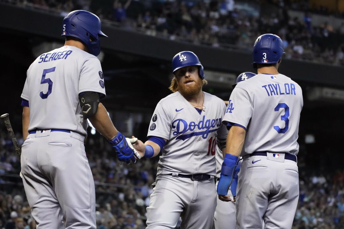Justin Turner celebrates with Corey Seager and Chris Taylor after scoring runs on a double by Albert Pujols.