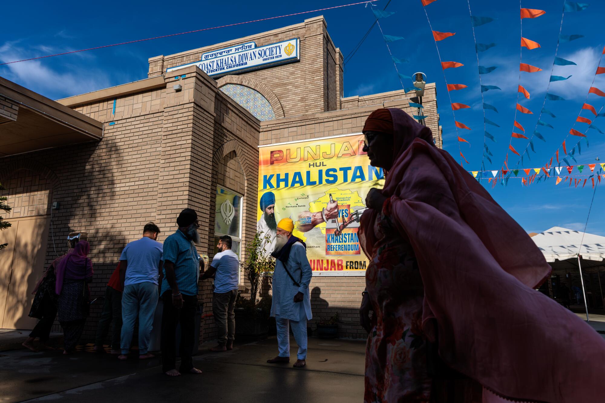 People stand near a building bearing a large yellow banner with the word "Khalistan" 
