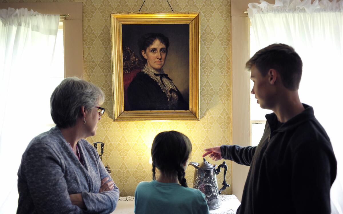 Museum visitors view a portrait of author Louisa May Alcott by artist George Healy at Orchard House in Concord, Mass.