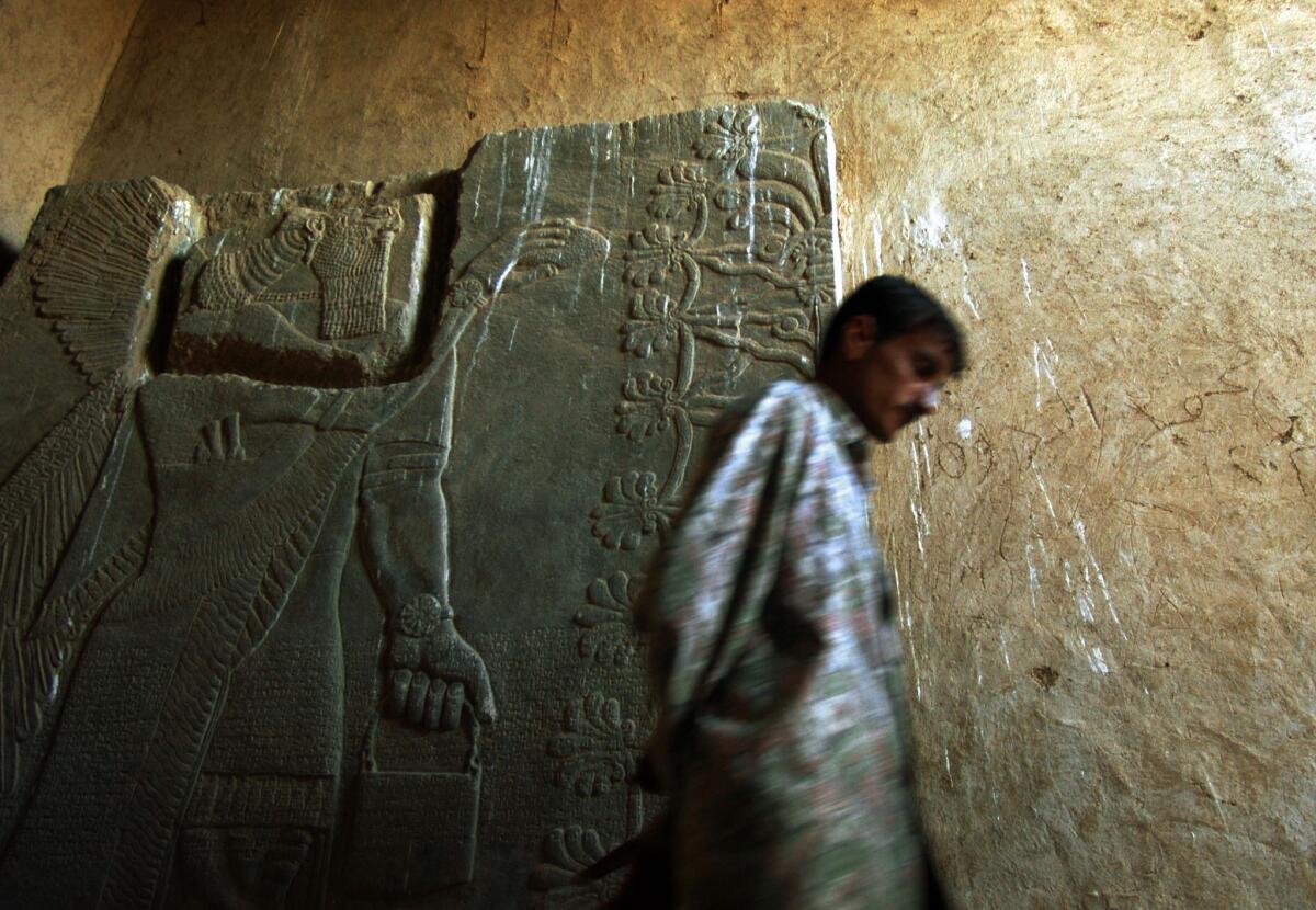 A guard at the ancient city of Nimrud, Iraq, walks in 2003 past an alabaster bas relief dating to between 800 and 900 BC.